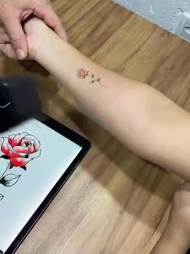 Tatuagem temporária de rosa colorida no braço